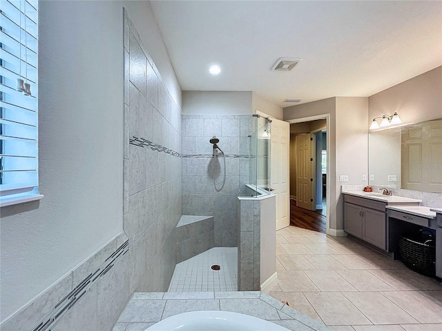 bathroom with tile patterned floors, vanity, and a tile shower