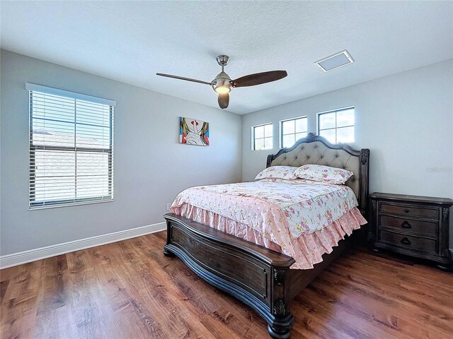 bedroom featuring ceiling fan, dark hardwood / wood-style flooring, and a textured ceiling