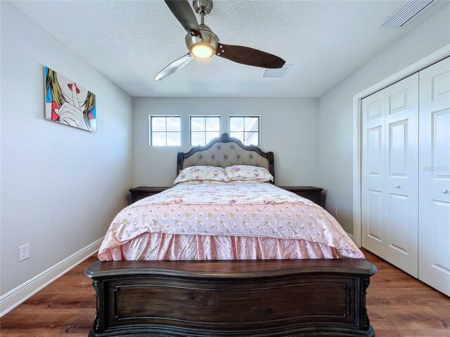 bedroom with ceiling fan, dark hardwood / wood-style flooring, a textured ceiling, and a closet