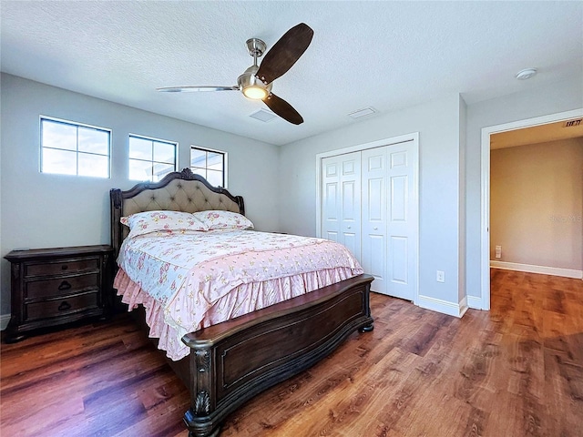 bedroom featuring a textured ceiling, a closet, ceiling fan, and dark wood-type flooring