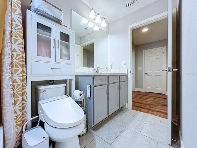 bathroom featuring a textured ceiling, vanity, hardwood / wood-style flooring, and toilet