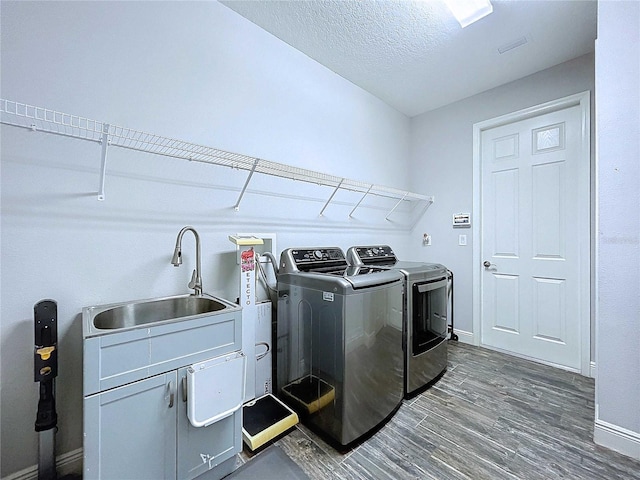 laundry area with cabinets, dark wood-type flooring, sink, washer and dryer, and a textured ceiling