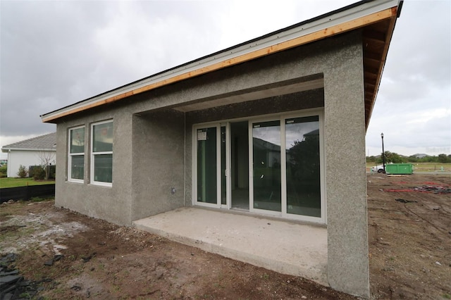 rear view of property featuring a patio and stucco siding