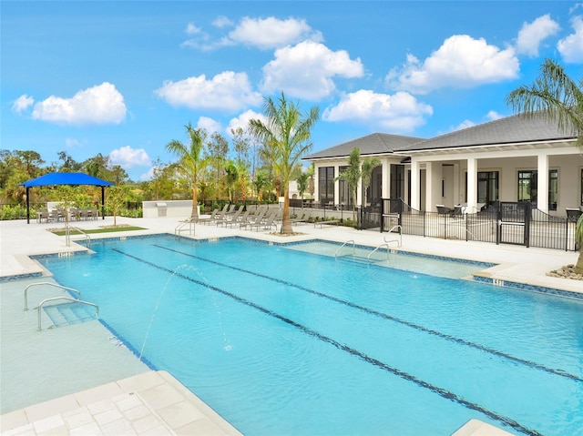 community pool with fence and a patio