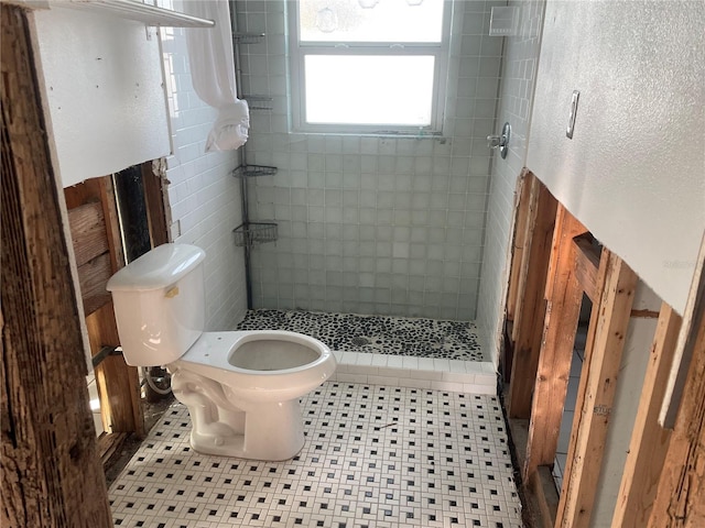 bathroom featuring tiled shower, tile patterned floors, and toilet