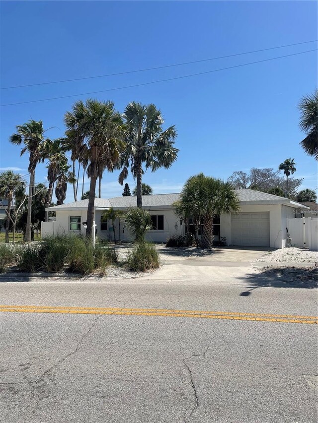 909 Mandalay Ave, Clearwater Beach, FL 33767 - view of front of home with concrete driveway, a garage, stucco siding, and fence