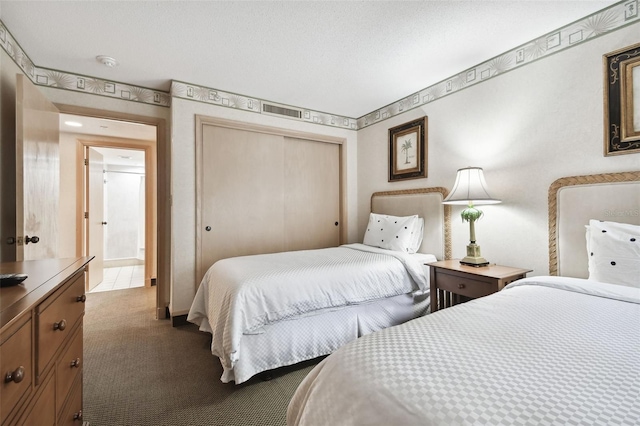 bedroom featuring a textured ceiling, dark carpet, and a closet