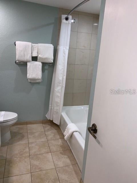 bathroom featuring tile patterned floors, shower / bath combo with shower curtain, and toilet