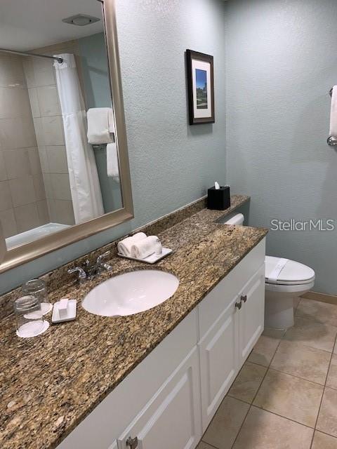 bathroom featuring tile patterned floors, vanity, toilet, and curtained shower