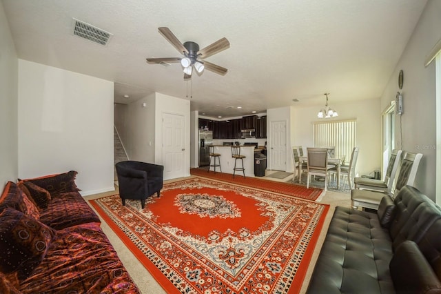 living room featuring a textured ceiling and ceiling fan with notable chandelier