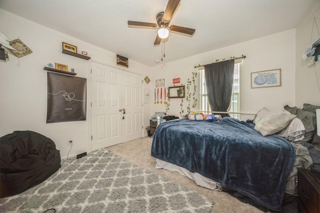 carpeted bedroom with ceiling fan and a closet