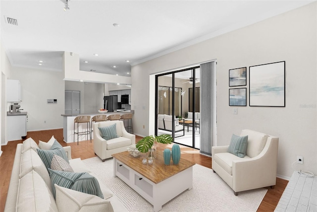 living room featuring light hardwood / wood-style floors, ceiling fan, and ornamental molding