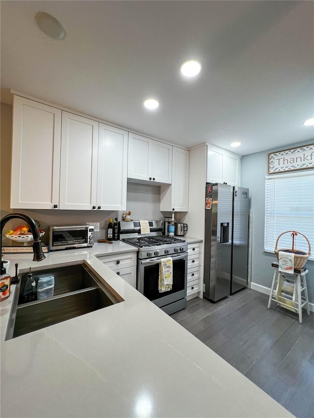 kitchen with white cabinets, sink, appliances with stainless steel finishes, and dark wood-type flooring