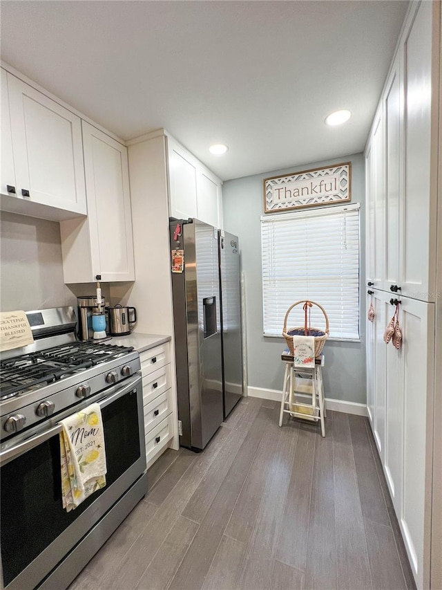 kitchen with hardwood / wood-style floors, stainless steel appliances, and white cabinetry