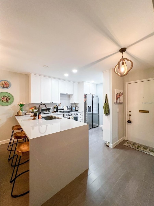 kitchen featuring kitchen peninsula, appliances with stainless steel finishes, white cabinetry, and sink