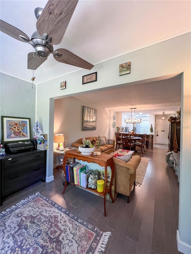 living room featuring ceiling fan with notable chandelier and dark hardwood / wood-style flooring