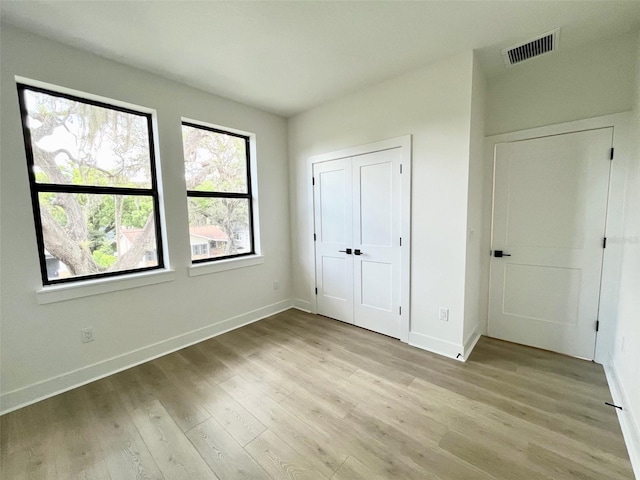 unfurnished bedroom with light wood-type flooring and a closet