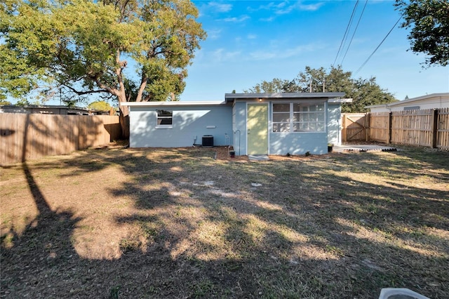 rear view of property featuring a lawn and central air condition unit