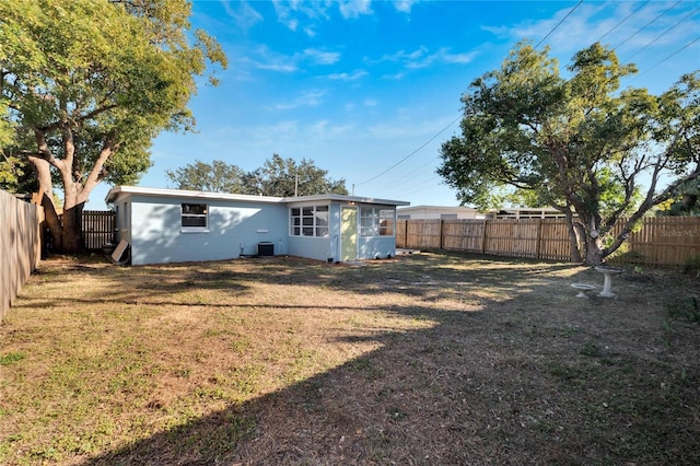 rear view of house featuring central AC unit and a lawn