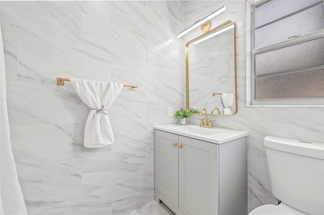 bathroom featuring vanity, toilet, and tile walls