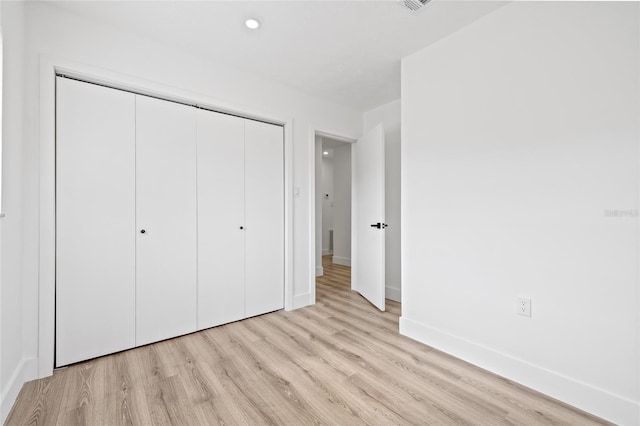 unfurnished bedroom featuring light wood-type flooring and a closet