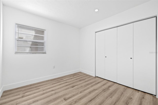 unfurnished bedroom with light wood-type flooring and a closet