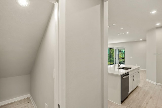 interior space with dishwasher, sink, light hardwood / wood-style flooring, and white cabinets