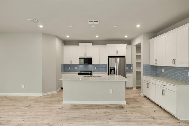 kitchen featuring appliances with stainless steel finishes, an island with sink, sink, white cabinets, and light hardwood / wood-style floors