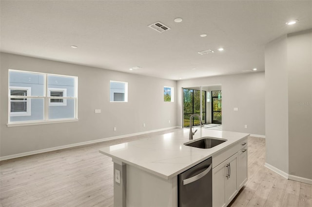 kitchen featuring sink, stainless steel dishwasher, an island with sink, light stone countertops, and white cabinets