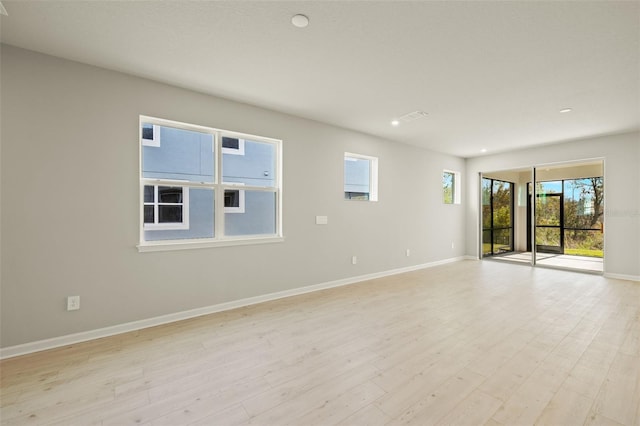 empty room with light hardwood / wood-style floors and a healthy amount of sunlight