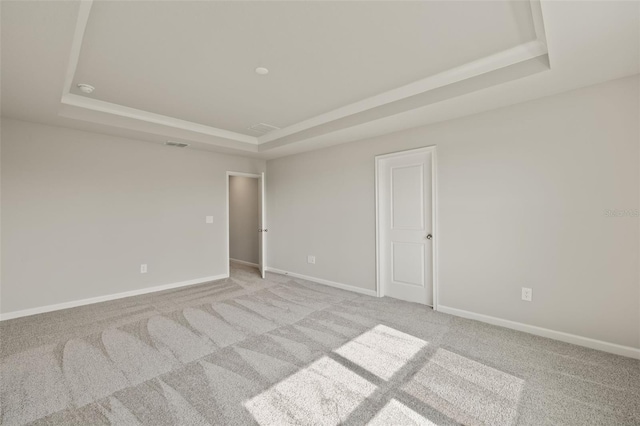 carpeted empty room featuring a raised ceiling