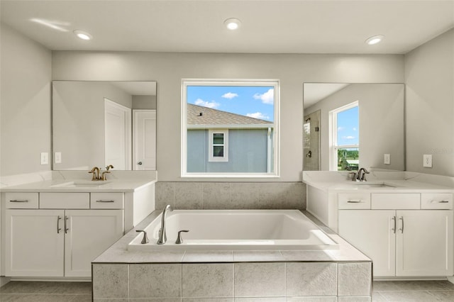 bathroom featuring vanity, tile patterned flooring, and a relaxing tiled tub