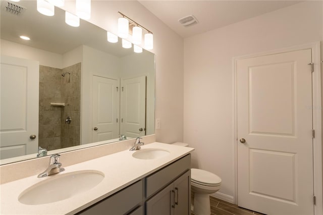 bathroom featuring tiled shower, hardwood / wood-style floors, vanity, and toilet