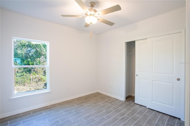 unfurnished bedroom featuring multiple windows, ceiling fan, a closet, and wood-type flooring