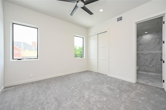 unfurnished bedroom with ceiling fan, light colored carpet, connected bathroom, and a closet