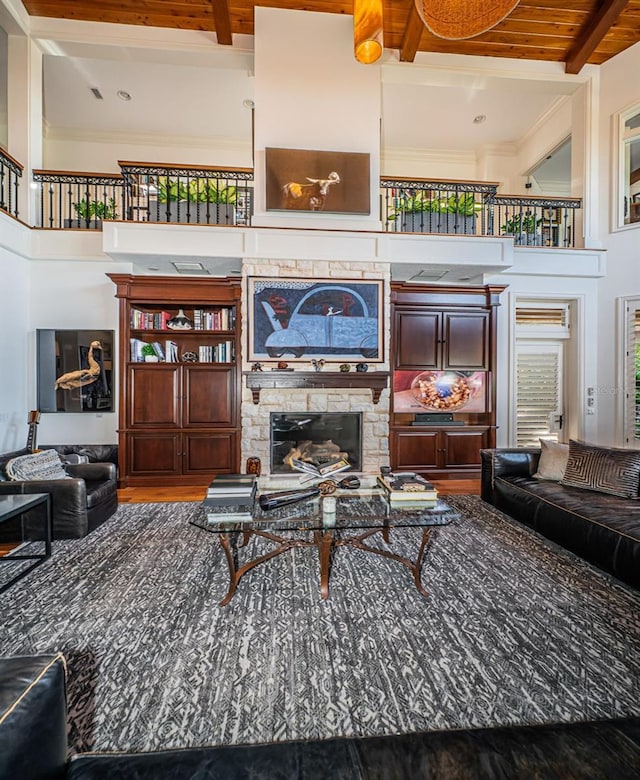 living room featuring a stone fireplace, beam ceiling, and wooden ceiling