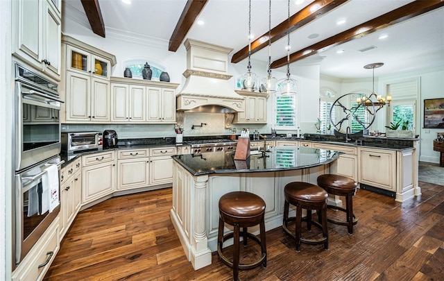 kitchen featuring backsplash, a center island with sink, and cream cabinets