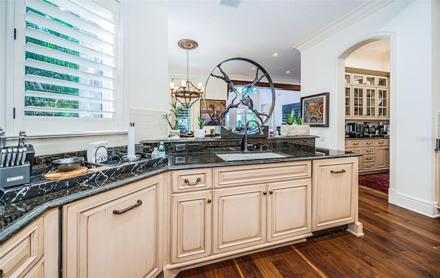 kitchen featuring pendant lighting, dark wood-type flooring, dark stone counters, sink, and crown molding