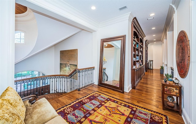 corridor with dark wood-type flooring, a textured ceiling, and ornamental molding