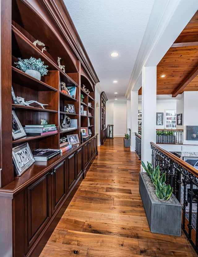 hallway featuring hardwood / wood-style flooring, wooden ceiling, ornamental molding, and beamed ceiling