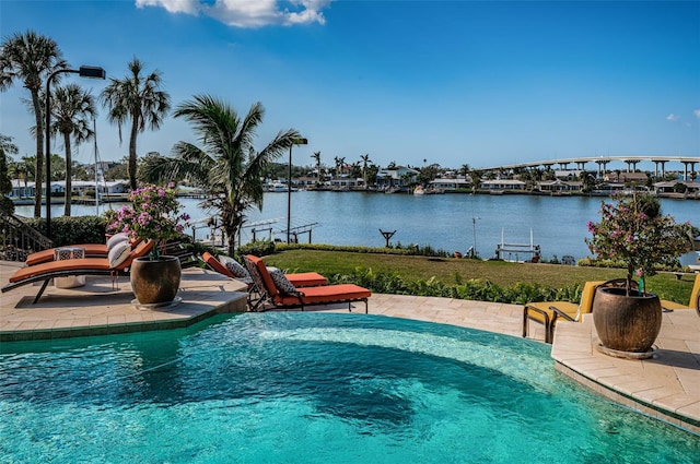 view of swimming pool with a lawn, a water view, and a patio