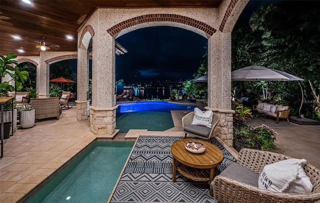 pool at night featuring a patio and outdoor lounge area