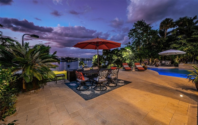 patio terrace at dusk featuring a water view