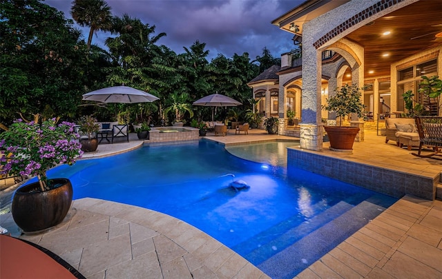 pool at dusk with an in ground hot tub