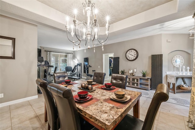 tiled dining space featuring a notable chandelier and a raised ceiling