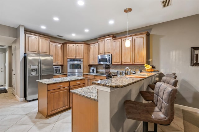 kitchen featuring a breakfast bar area, kitchen peninsula, pendant lighting, and stainless steel appliances