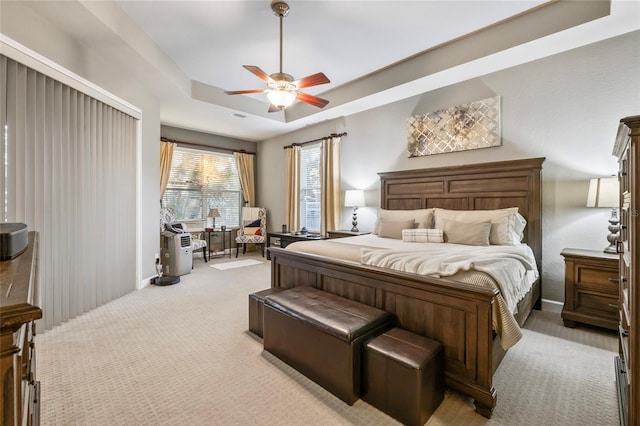 carpeted bedroom featuring a raised ceiling and ceiling fan