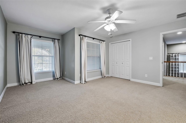 unfurnished bedroom featuring a closet, light colored carpet, and ceiling fan