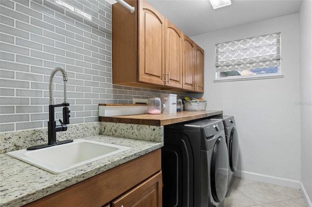 laundry area with separate washer and dryer, sink, light tile patterned floors, and cabinets