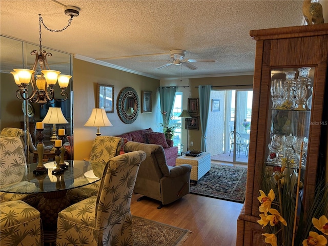 living room featuring hardwood / wood-style floors, ceiling fan with notable chandelier, a textured ceiling, and crown molding